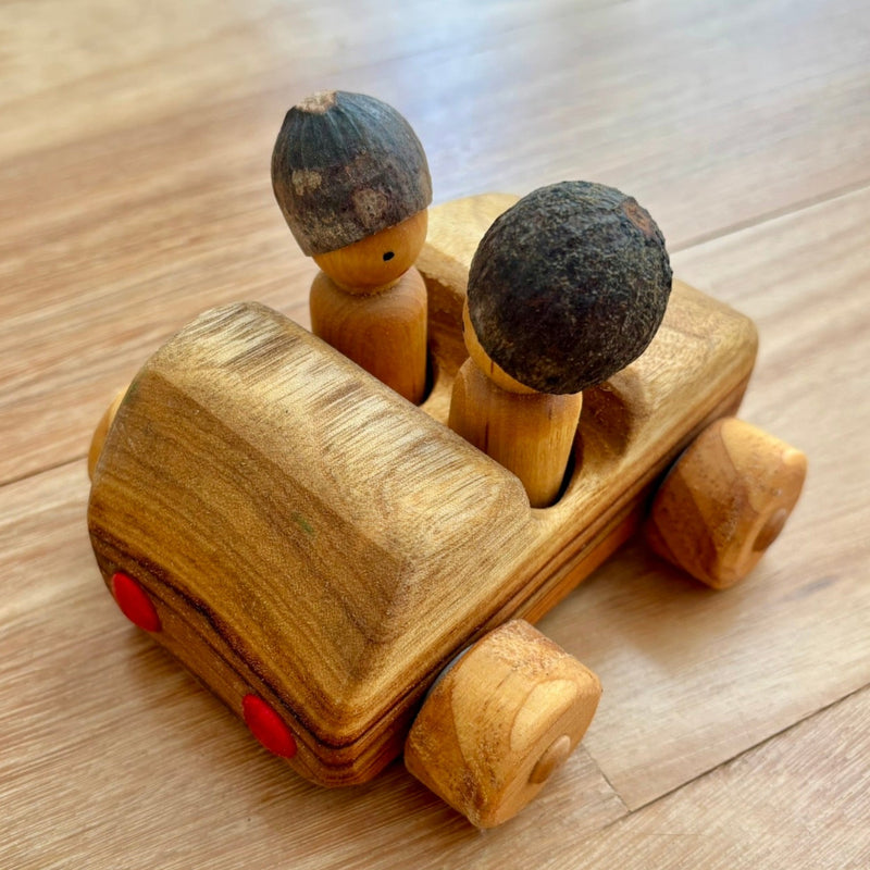 Wooden toy car with two small wooden figures, back view