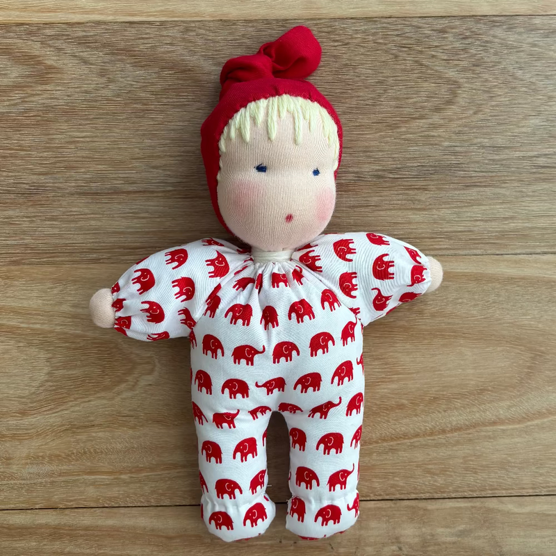 Soft Steiner / Waldorf doll with white outfit with red elephant pattern and red knot hat. 