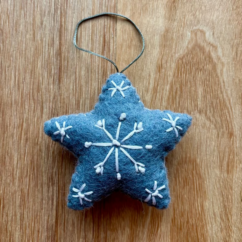 Blue star-shaped ornament with white snowflake patterns on a wooden surface
