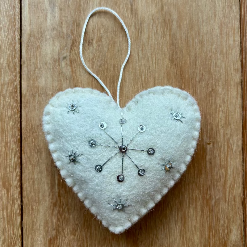Heart-shaped decorative ornament with beads on a wooden surface